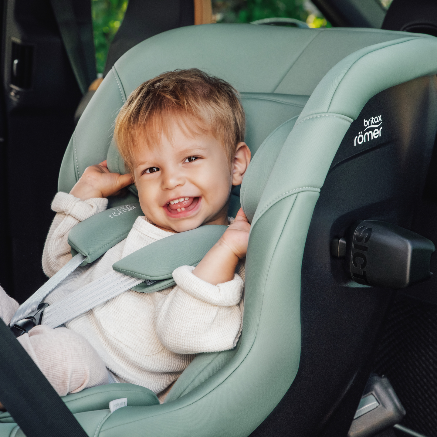 Ni&ntilde;o sonriente asegurado en la silla de auto MAX-SAFE PRO en Jade Green.