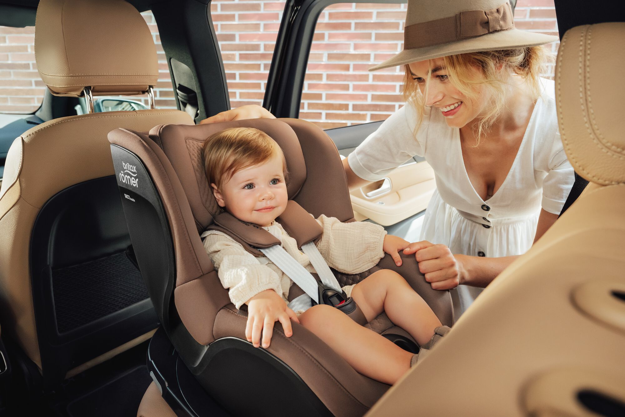 Niño pequeño asegurado en una silla de coche DUALFIX 5Z toddler car seat, con su madre a su lado.